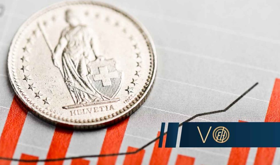 Zbliżenie na srebrną monetę franka szwajcarskiego, leżącą na tle szarego wykresu słupkowego z rosnącą czarną linią