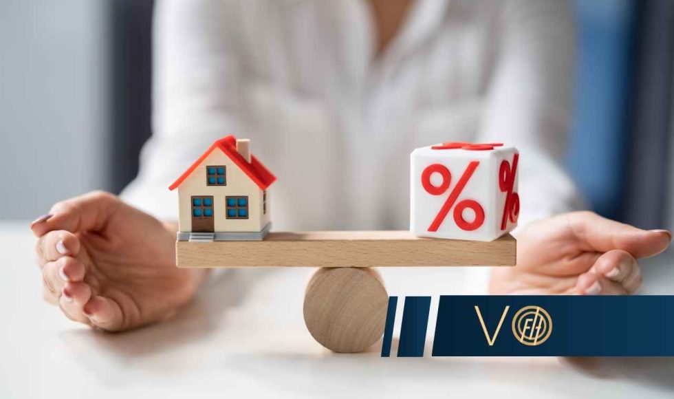 Kredytobiorca siedzi przy stole z wagą, po lewej figurka domu, po prawej figurka procenta, symbolizująca decyzję finansową