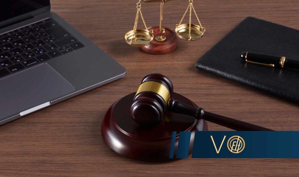 Młotek sędziowski na podstawce obok laptopa, wagi, zeszytu i długopisu - symbol sprawy frankowicza w sądzie