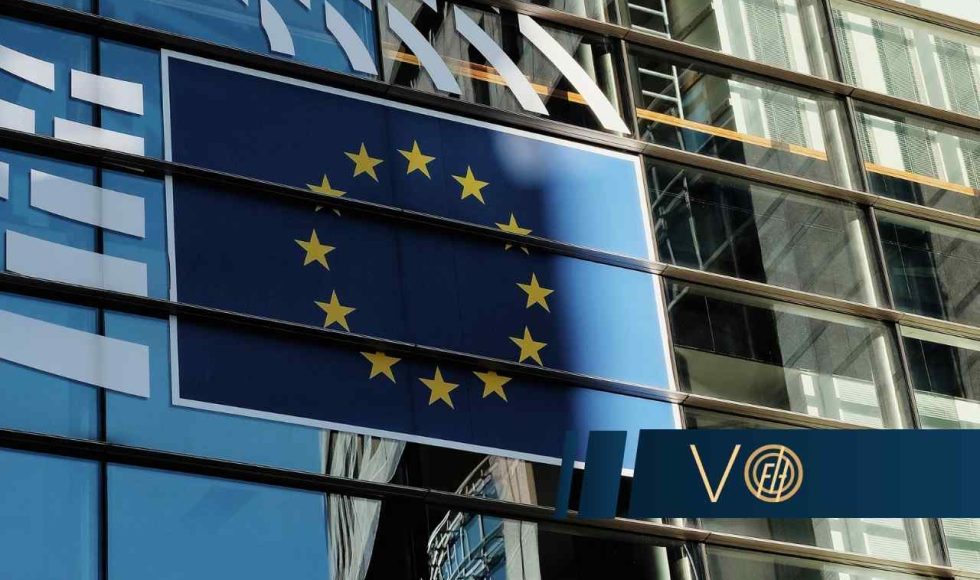 Flaga Unii Europejskiej jest zawieszona na fasadzie nowoczesnego, przeszklonego budynku