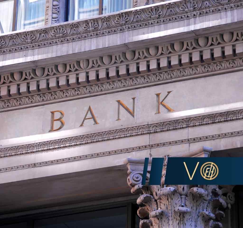 Zbliżenie na zdobioną fasadę klasycznego budynku z dużym napisem „BANK” wykonanym ze złotych liter
