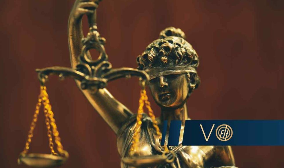 Złota statuetka Temidy, rzymskiej bogini sprawiedliwości, z zasłoniętymi oczami, trzymającej wagę w dłoni.