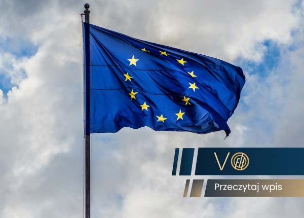 Flaga Unii Europejskiej powiewająca na maszcie na tle zachmurzonego nieba