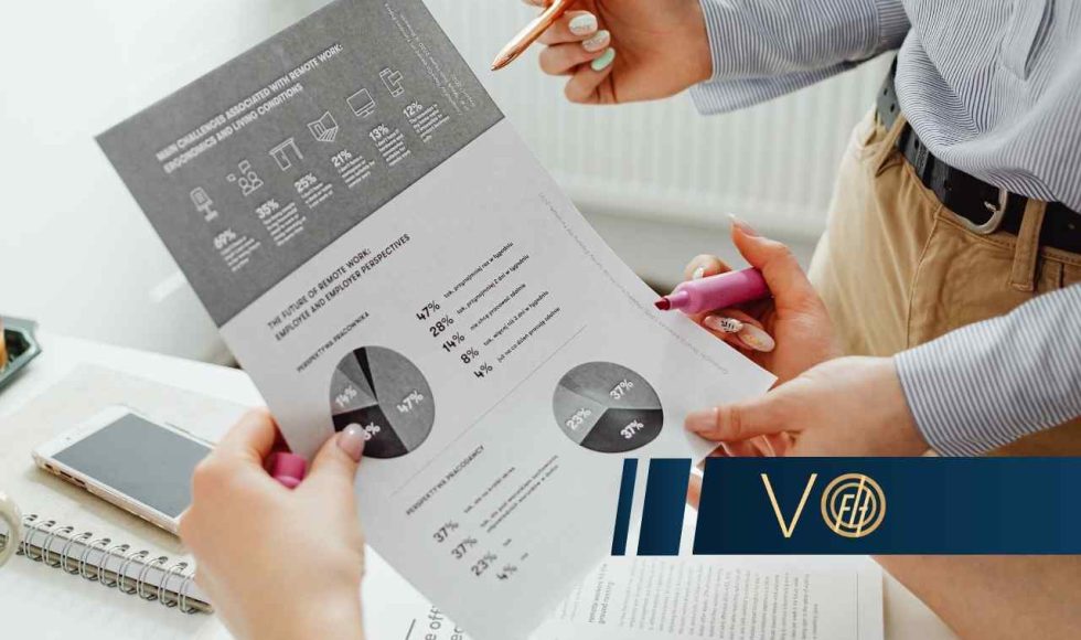 Dwie osoby analizują dokumenty z wykresami kołowymi i danymi statystycznymi, trzymając w dłoniach długopis i różowy zakreślacz.