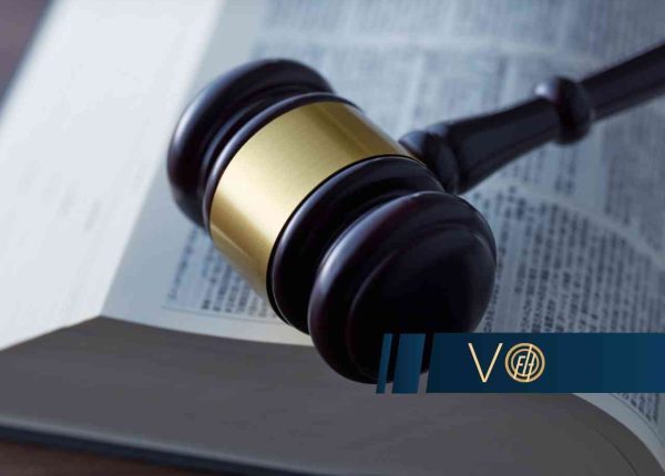 Młotek sędziowski leżący na otwartej księdze z tekstami prawnymi