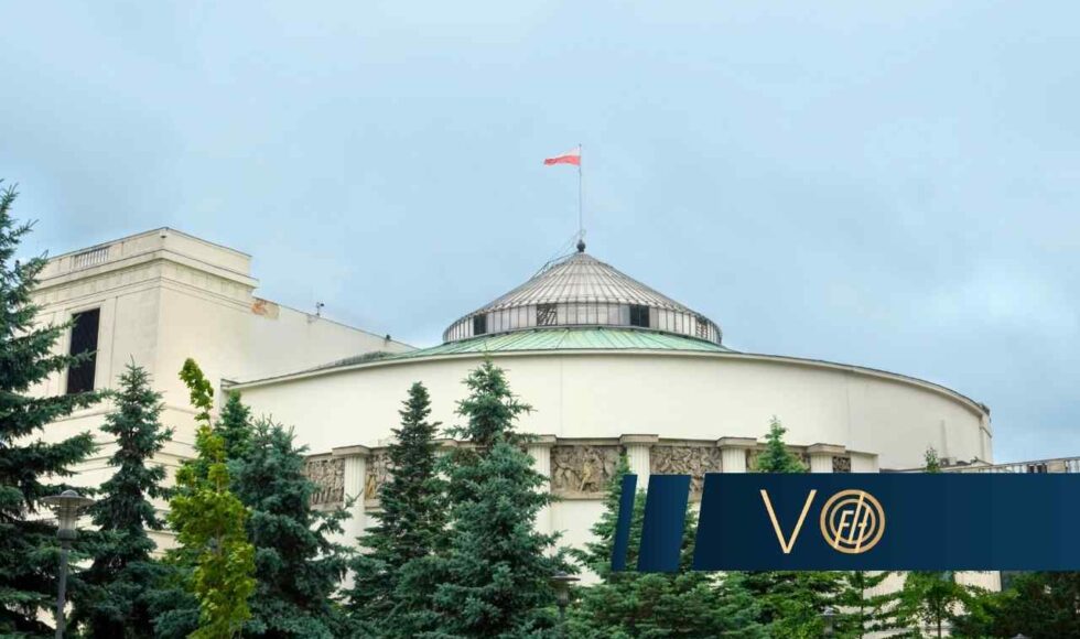 Widok na charakterystyczny, okrągły budynek Sejmu Rzeczypospolitej Polskiej w Warszawie z polską flagą na dachu, częściowo zasłonięty przez zielone drzewa iglaste. W prawym dolnym rogu umieszczono ciemnoniebieski pas z logotypem Votum Finance Help.