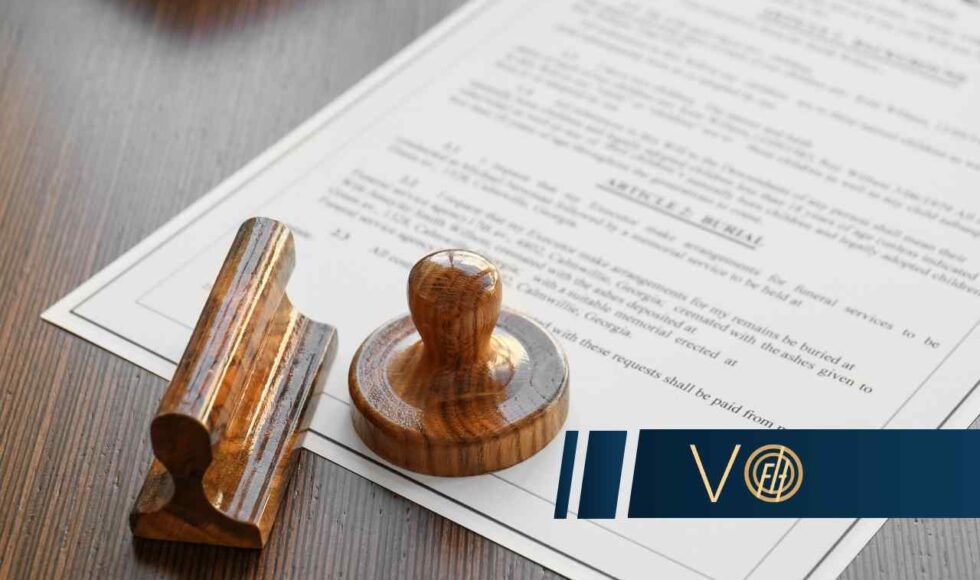 Formal legal document with a wooden stamp and seal on a wooden surface, a blue logo overlay in the corner.