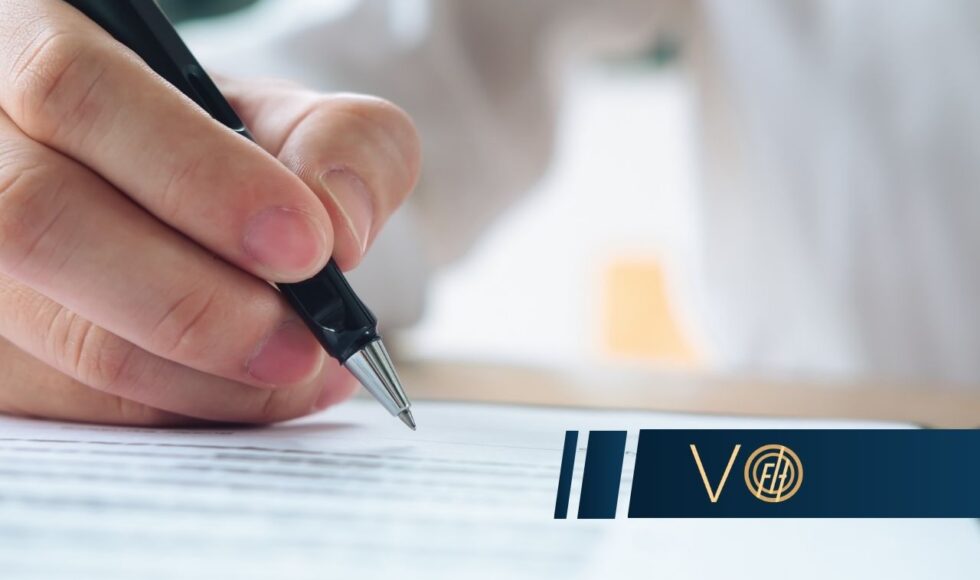 Close-up of a hand signing a document with a pen, a blue logo banner across the bottom.